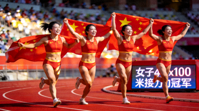 中国田径运动员在女子4x100米接力夺冠后手持国旗绕场庆祝